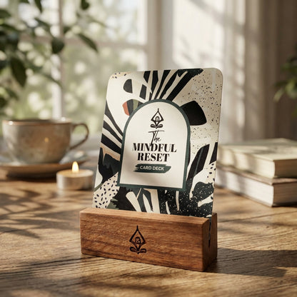 Card deck titled 'The Mindful Reset' on a wooden stand with a blurred background of books and a candle resembling the stress relief provided by practicing mindfulness exercises.