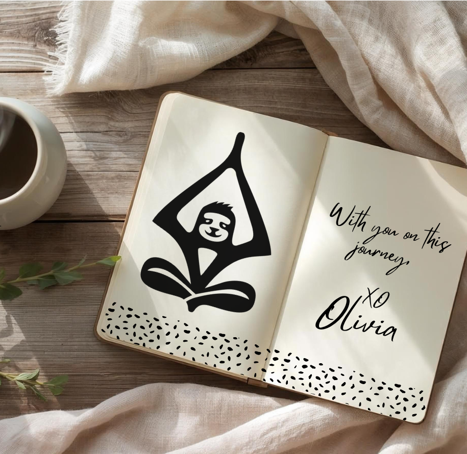 Open notebook with a black illustration of Tranquilivia's sloth mascot Olivia and a gentle note from her on a wooden surface with a mug and fabric.